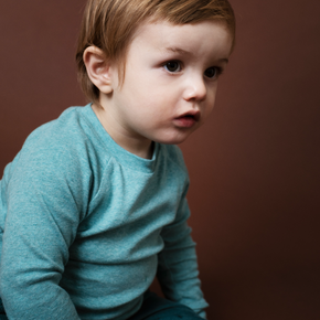 Child wearing a teal shirt against a brown background