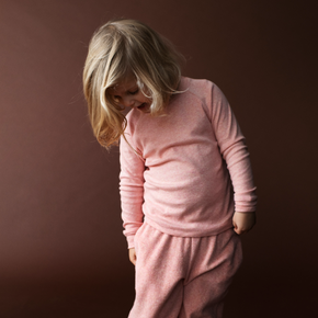 Child wearing a pink outfit against a brown background
