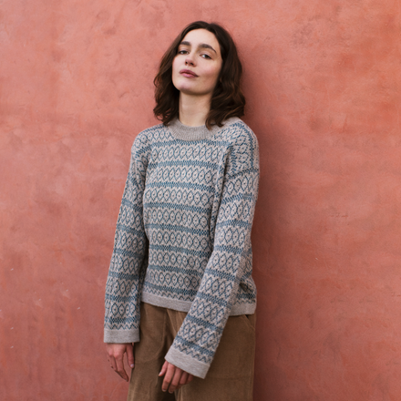 Woman wearing a patterned sweater against a pink wall