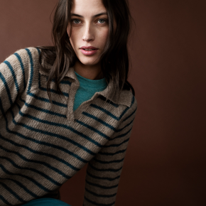 Woman wearing a striped sweater against a brown background