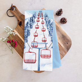 Tea towel with. red ski lift design on wooden board