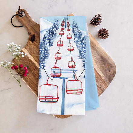 Tea towel with. red ski lift design on wooden board