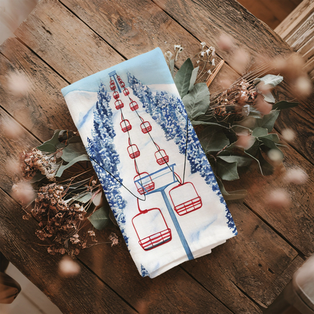 Teal towel with red ski lift imagery on wooden table