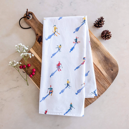 White towel with skier pattern on a wooden board with decorative elements