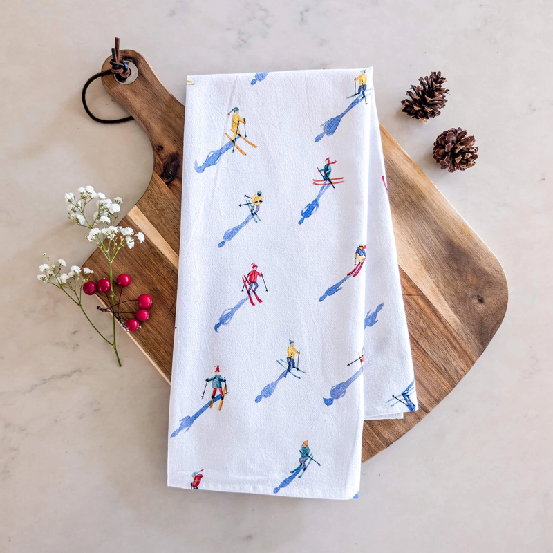 White towel with skier pattern on a wooden board with decorative elements