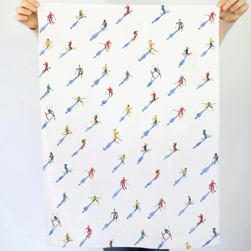 Tea towel with a pattern of small skiers on a white background