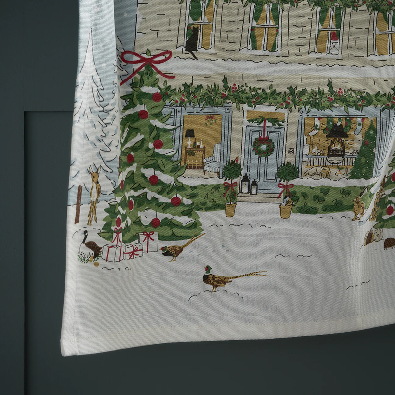 Decorative towel with a Christmas scene featuring a house, tree, and presents.