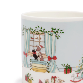 Ceramic mug with festive design of a dog in a Santa hat looking out a window with Christmas decorations.
