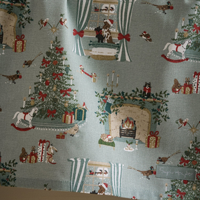 Christmas-themed tea towel with trees, presents, and animals on a light blue background
