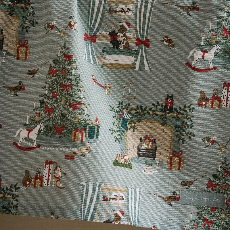 Christmas-themed tea towel with trees, presents, and animals on a light blue background