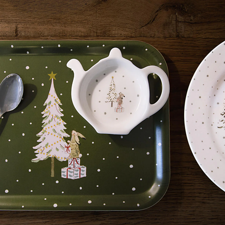 Green tray with Christmas design, white tea bag holder, and plate on a wooden surface