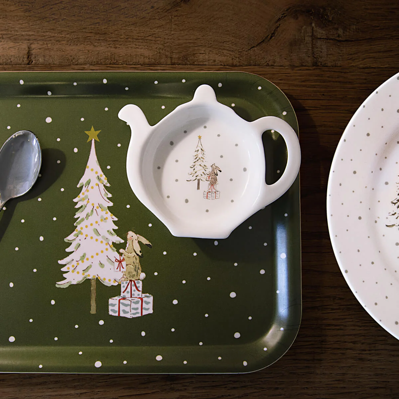 Green tray with Christmas design, white tea bag holder, and plate on a wooden surface