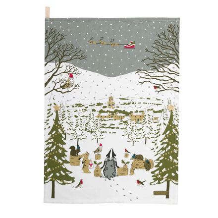 Festive tea towel with Santa Claus in a sleigh, trees, and animals in a snowy landscape.