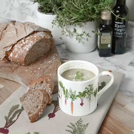 Mug of soup with bread and herbs on a marble surface