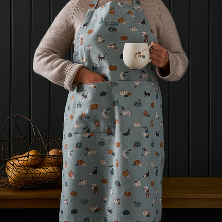 Person wearing a patterned apron holding a mug against a dark wooden background