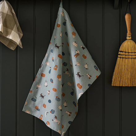Decorative towel with animal pattern hanging on a dark wooden wall next to a broom.