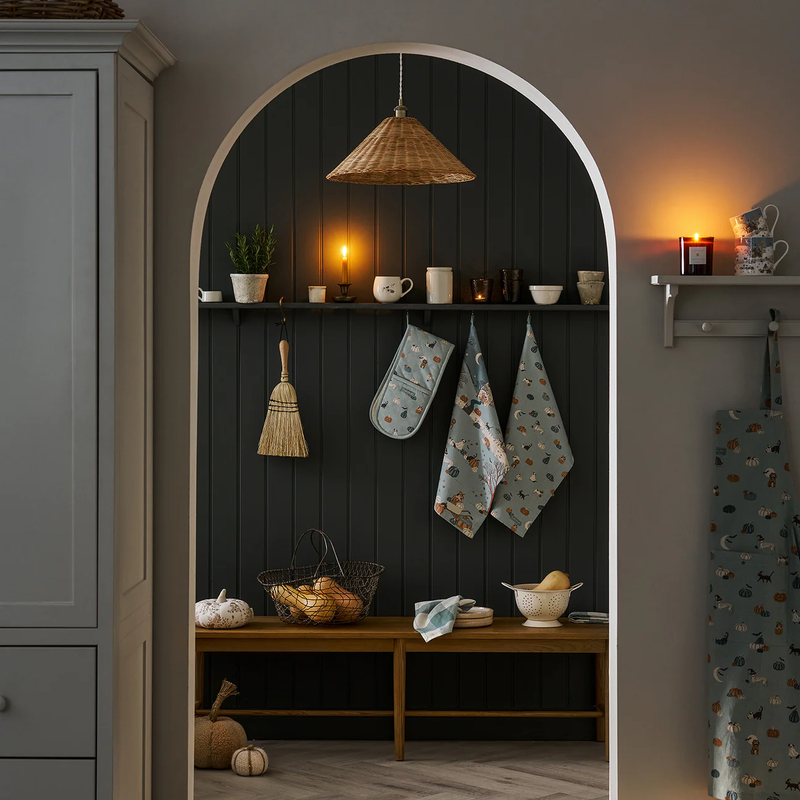 Archway into a kitchen with shelves, decorative items, and a broom.