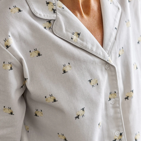 Close-up of a light gray pajama shirt with small sheep print on a neutral background