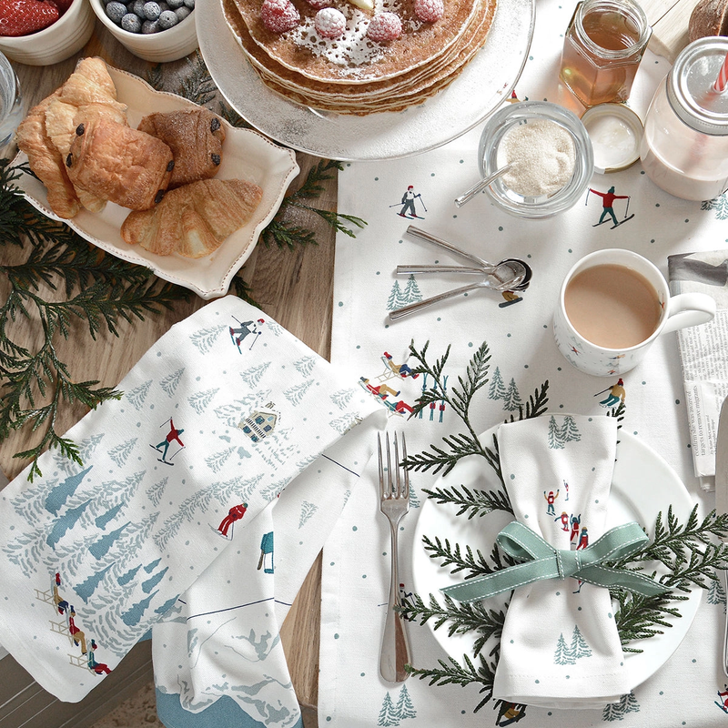 Festive table setting with ski themed tea towel, napkins, and mug