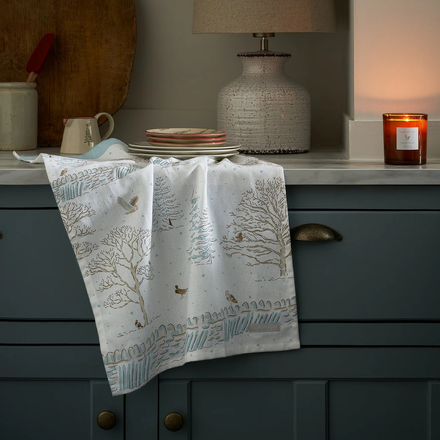 Tea towel with nature design hanging on a kitchen cabinet