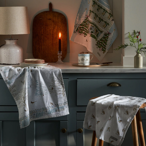 Kitchen scene with patterned towels on a counter and chair, candlelit ambiance.