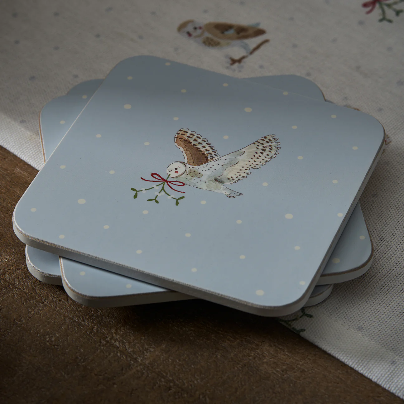 Stack of coasters with owl design on a snowy background