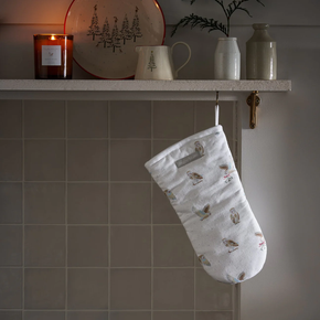 White oven mitt with owl pattern hanging on a tiled wall