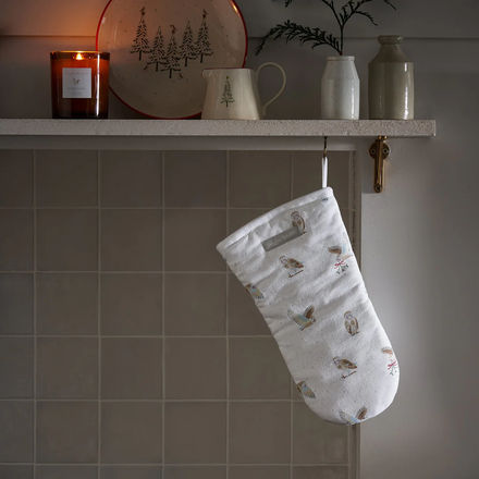 White oven mitt with owl pattern hanging on a tiled wall