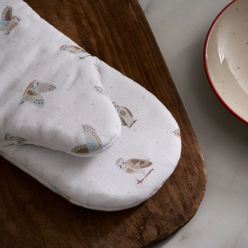 White oven mitt with owl pattern on a wooden surface
