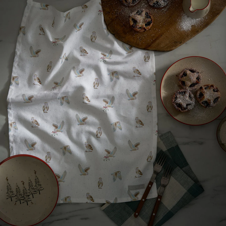 White tea towel with owl pattern on a table with plates of dessert