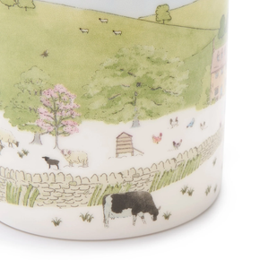 A white fine bone china mug with a spring cottage scene design, including a cottage, blossoming trees, and baby animals.
