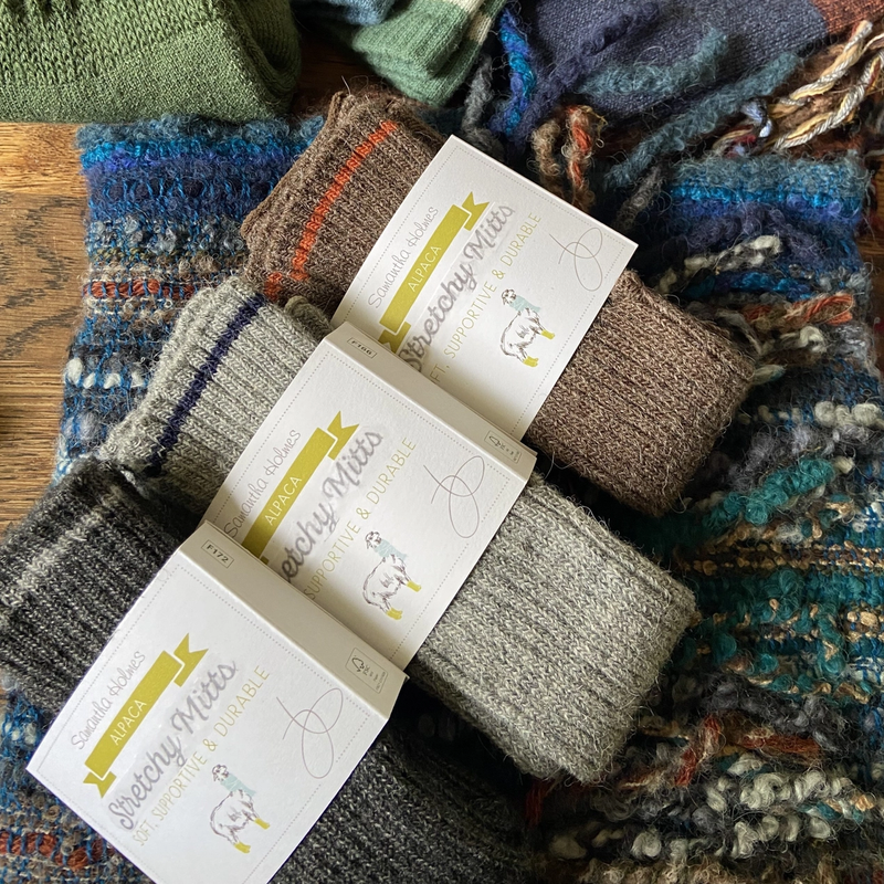 Knitted wrist warmers with a label on a colorful fabric background