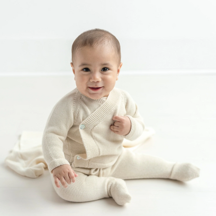 Baby wearing a cream-colored outfit on a white background