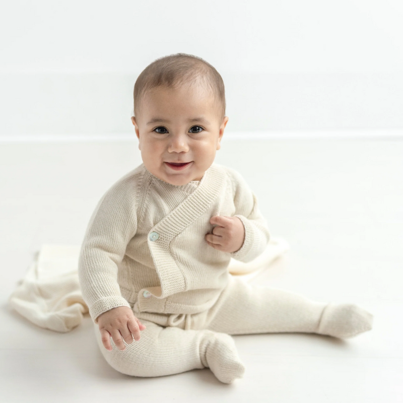 Baby wearing a cream-colored outfit on a white background