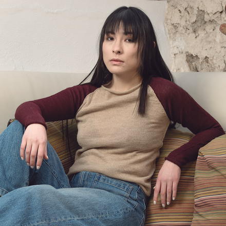 Woman sitting on a couch in a casual setting with a stone wall and pottery in the background