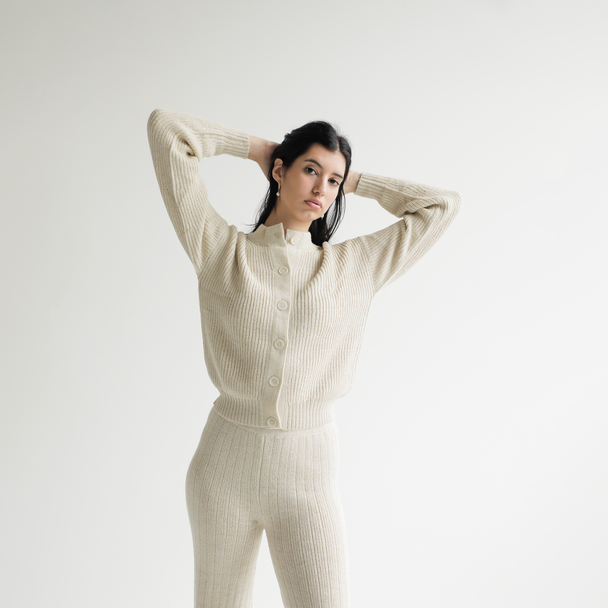Woman wearing a cream ribbed knit outfit against a white background
