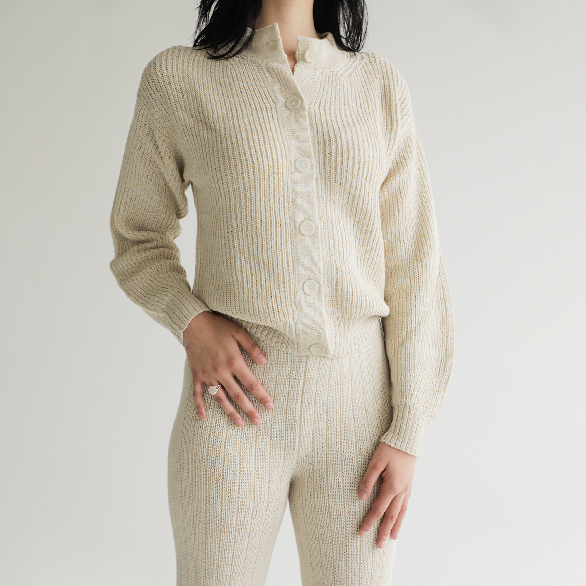 Person wearing a cream ribbed knit outfit on a plain background