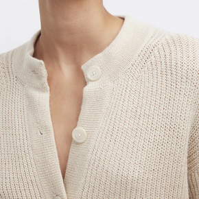 Close-up of a cream knitted cardigan with buttons on a white background