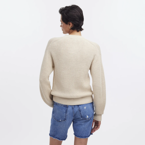 Person wearing a cream sweater and blue shorts on a white background