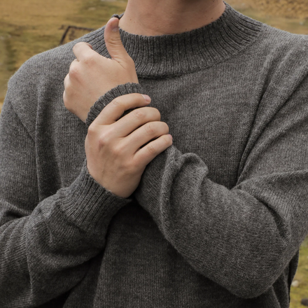 Person wearing a gray sweater with a blurred natural background
