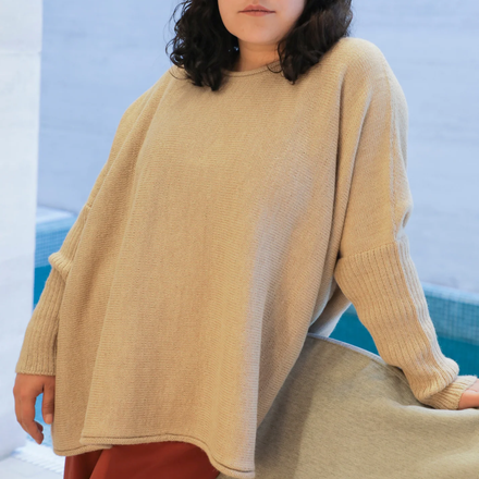 Person wearing a white sweater with a blurred background