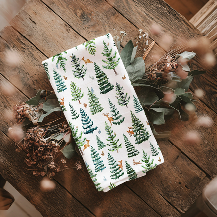Towel with forest pattern on a wooden surface with dried flowers