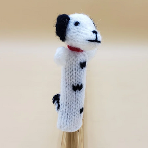 A white finger puppet with black spots and a red collar, resembling a dog.
