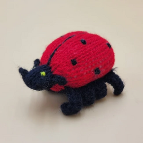 Knitted ladybug finger puppet on a beige background