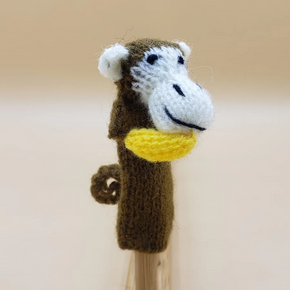 Knitted monkey finger puppet with a yellow banana on a beige background