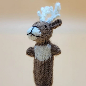Knitted reindeer finger puppet with white antlers on a beige background