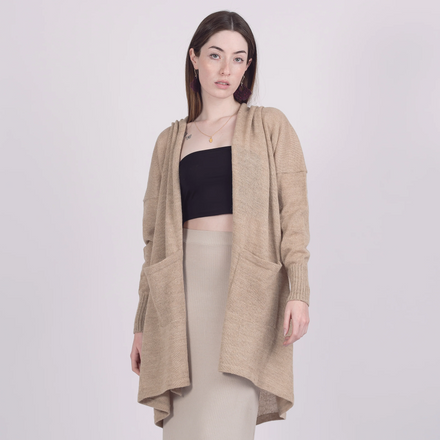 Woman wearing a beige cardigan, black top, and beige pants on a white background