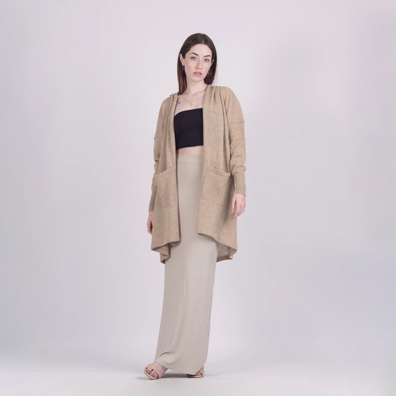 Woman wearing a beige cardigan, black top, and beige pants on a white background