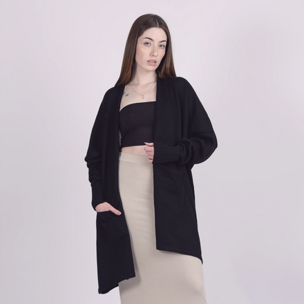 Woman wearing a black cardigan over a black top and beige skirt on a white background