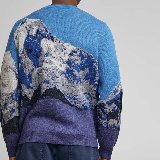 Kuna Huarascan Sweater - model wearing light blue and dark blue sweater with mountain range on a neutral background